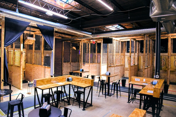 Our venue interior with wooden tables and throwing lanes in the background.